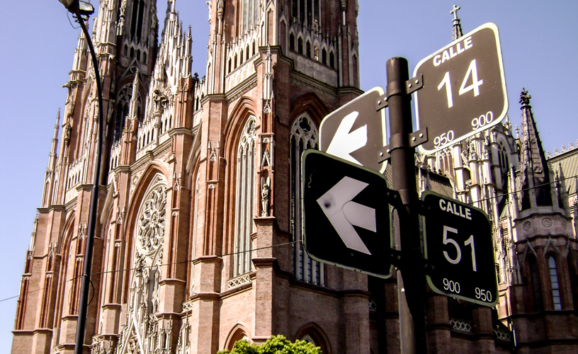 una imagen del cartel de la intersección de las calles 14 y 51 donde se encuentra la plaza principal (Plaza Moreno) y de fondo la catedral